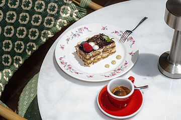 A piece of cake on a plate next to a cup of coffee