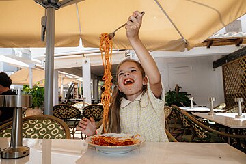 A little girl is eating spaghetti with a fork